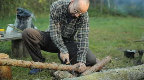 Man sawing a small tree camp saw. Near lit a fire and lay the tourist stuff Stock Footage 64444052