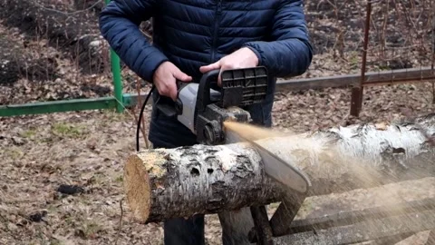 A man saws a birch log on a special stand with an electric saw Stock Footage 209225508