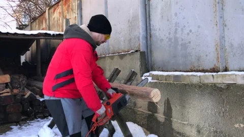 A man saws logs using an electric saw. Outdoor shot on a winter day. Stock Footage 173089664