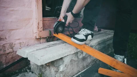 A man saws a thin board with a grinder. on the threshold of his workshop. Stock Footage 276091878