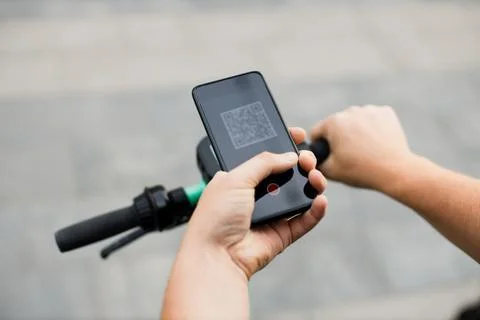 Man scan QR code by smart phone to unlock and rent electric push scooter on Stock Photos