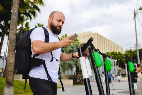 Man scanning qr code with his phone for electric scooter renting. Stock Photos