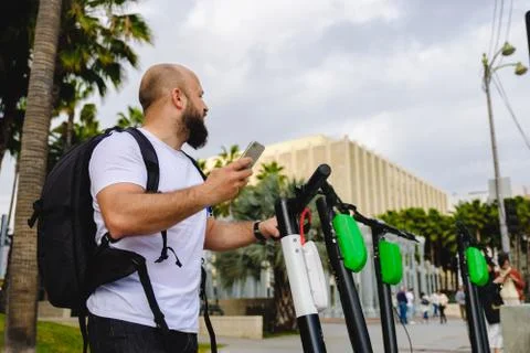 Man scanning qr code with his phone for electric scooter renting. Stock Photos