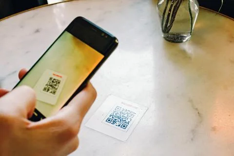 Man scanning the QR code with mobile phone at the restaurant. Stock Photos