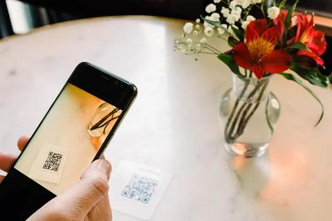 Man scanning the QR code with mobile phone at the restaurant. Stock Photos