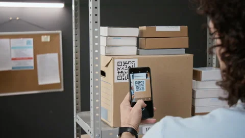 Man Scanning Qr Code on Package Using Smartphone in Warehouse Stock Footage 346069958