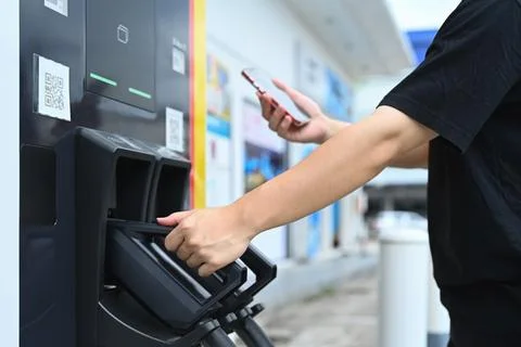 Man scanning QR code with smartphone to paying for electric car battery charging Foto stock