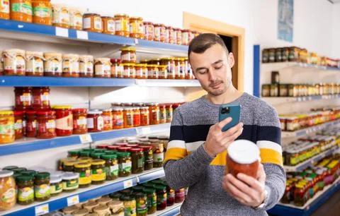 Man scans a barcode or QR code using a smartphone on a jar of delicious lecho in Foto stock