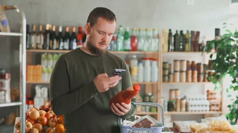 Man scans the label of tomato juice on his mobile phone. Modern methods of Stock Footage 316575938