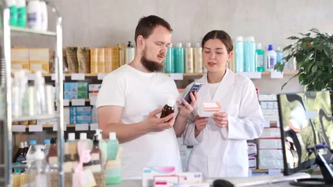 Man scans QR code on box cough syrup label. Female pharmacist offers various Stock Footage 318430292