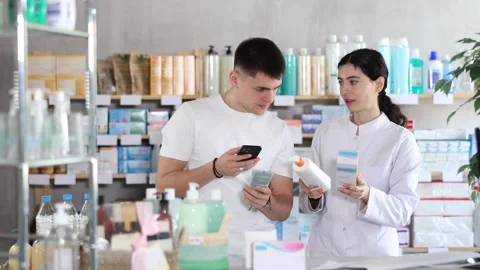 Man scans QR code on box skin cream label. Female pharmacist offers to choose Stock Footage 321326499