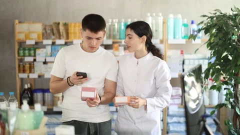 Man scans QR code on box pills label. Female pharmacist offers to choose the 動画素材 341429858