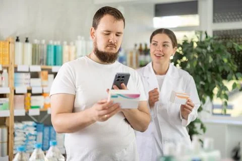Man scans QR code on box pills label. Female pharmacist offers to choose right Foto stock