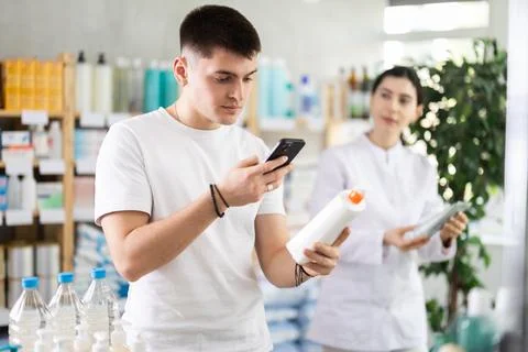 Man scans QR code on box skin cream label. Female pharmacist offers to choose Fotos de archivo