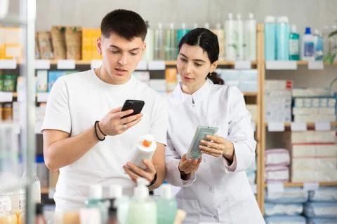 Man scans QR code on box skin cream label. Female pharmacist offers to choose Stock-Fotos