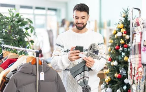 Man scans the qr code of the label of hats against the background of a Christmas Stockfoto's