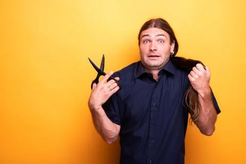 Man with scared look thinking of cutting hair with scissors Stock Photos