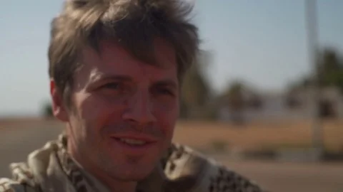 Man in a scarf riding a bike and looking at the camera slow motion Stock Footage