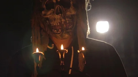 Man with scary halloween mask holding candles back lit by light Stock Footage 104193953