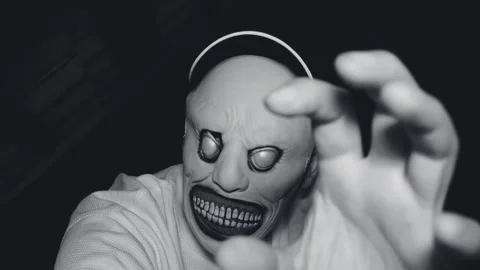 A man in a scary monster mask in a dark attic. Black and white video Stock Footage 285371837