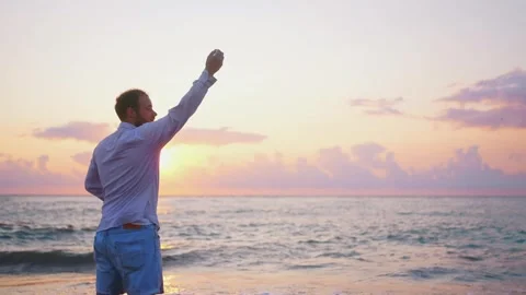 A man scatters ashes from a cremation urn over the ocean at sunset beautiful sun Stock Footage 247273860