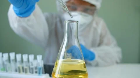 Man scientist is analyzing with a pipette a liquid golden yellow to extract Stock-Footage 140264644