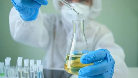 Man scientist is analyzing with a pipette a liquid golden yellow to extract Stock Footage 147930462