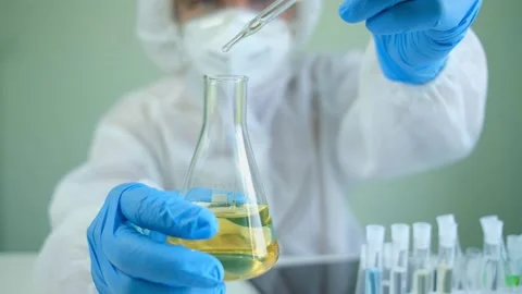 Man scientist is analyzing with a pipette a liquid golden yellow to extract Stock Footage 147930494