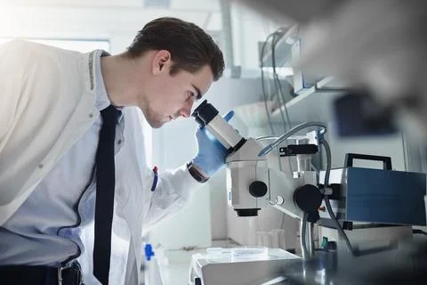 Man, scientist and forensic study in laboratory with microscope for medical.. Фото