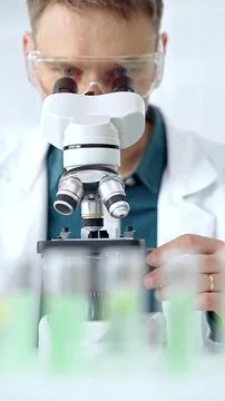Man scientist with protective glasses using microscope in laboratory Stock Photos