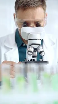 Man scientist with protective glasses using microscope in laboratory Stock-Fotos