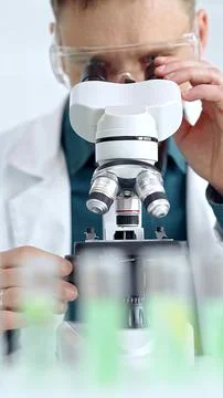 Man scientist with protective glasses using microscope in laboratory Stock Photos