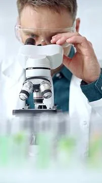 Man scientist with protective glasses using microscope in laboratory Foto stock