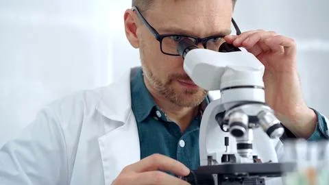 Man scientist with protective glasses using microscope in laboratory Stock Photos