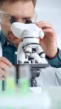 Man scientist with protective glasses using microscope in laboratory Stock Photos