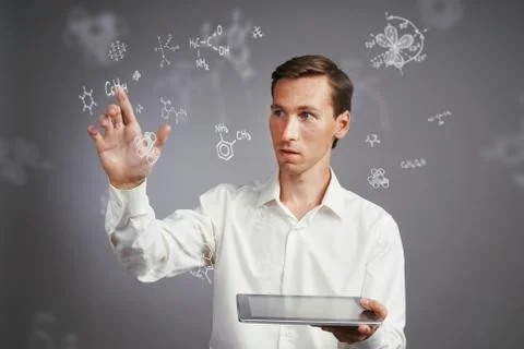 Man scientist with tablet pc working with chemical formulas on gray background. Stock Photos