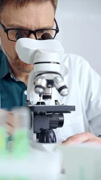 Man scientist using microscope in laboratory. Microbiology science concept Stock Photos