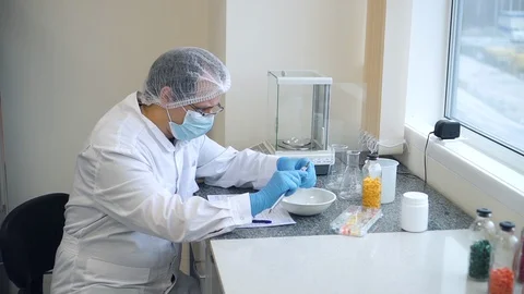 Man scientist is working with samples of pills while sitting at table in Stock Footage 129523759