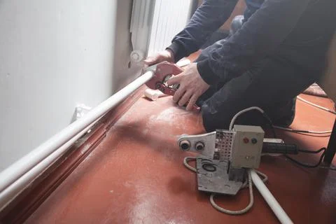 Man with scissors cutting plastic pipe. Stock Photos