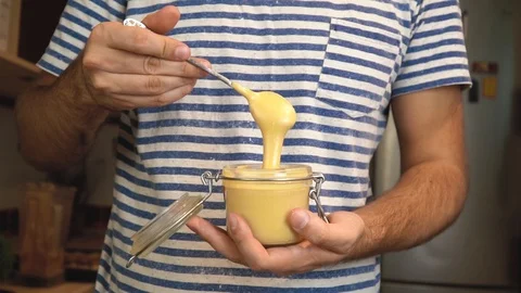 Man scooping and pouring peanut butter. Creamy smooth peanut butter. 库存影片 122805741