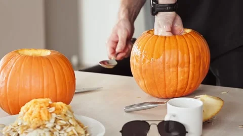 Man Scooping Out Pumpkin With Spoon For Carving Stock Footage 313480852