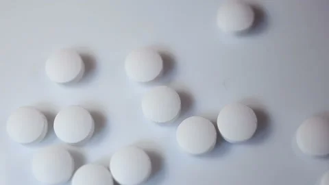 The man scoops up small white round pills with his hand. On a white background, Stock Footage 144643644