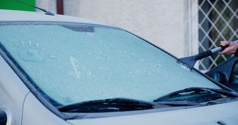 Man with scraper scraping ice from car front window Stock Footage 104982308