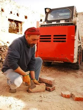Man Scraping Bricks in Front of Bobcat Skid Loader Stock Photos