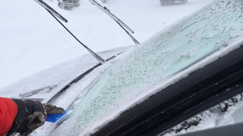Man scraping ice from car windshield during blizzard Stock Footage 319554876