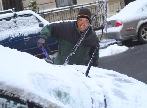 Man scraping snow from windshield Stock Photos