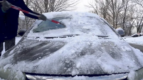 Man Scraps Snow off Windshield of a Grey Car Stock Footage 147684648