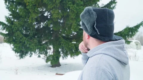 A man scratches his beard, thinking about whether to cut down a tree or not. Stock Footage 263051885
