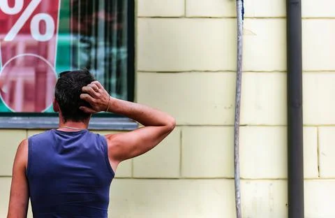 Man scratching head while looking at percentage sign in window display Stock Photos