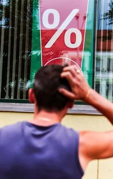 Man scratching head while looking at percentage sign in window display Stock Photos